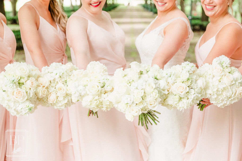 all-white bridal bouquets held by bridesmaids in blush pink Bella Bridesmaid gowns