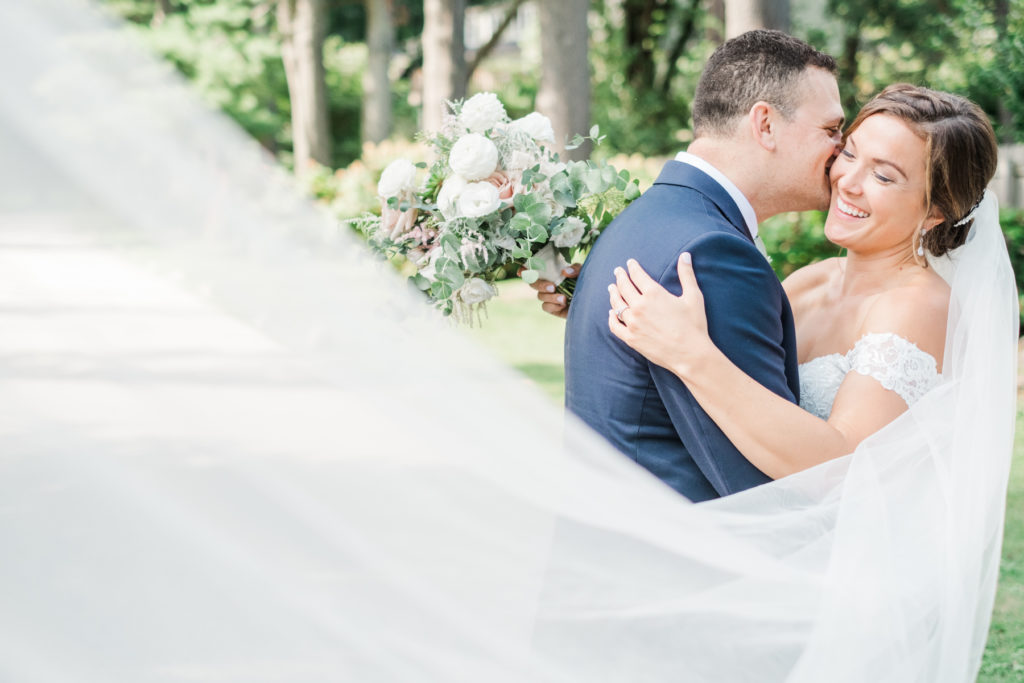bride and groom portrait on wedding day with long swooping veil
